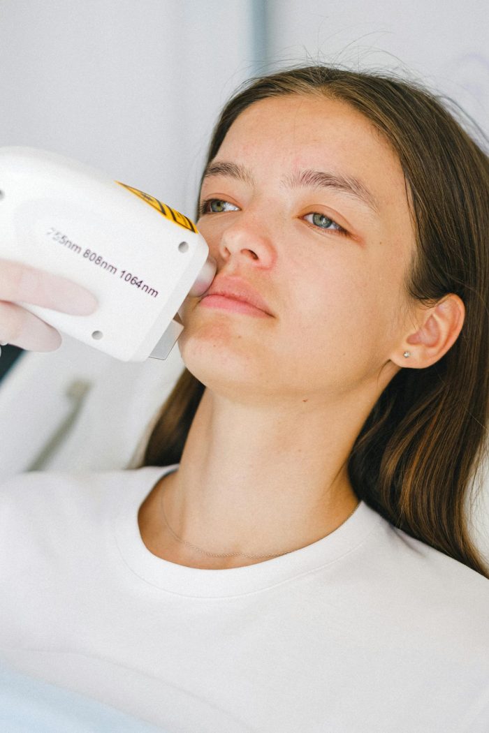 Calm woman client lying in medical room during visit to cosmetologist on low level laser therapy