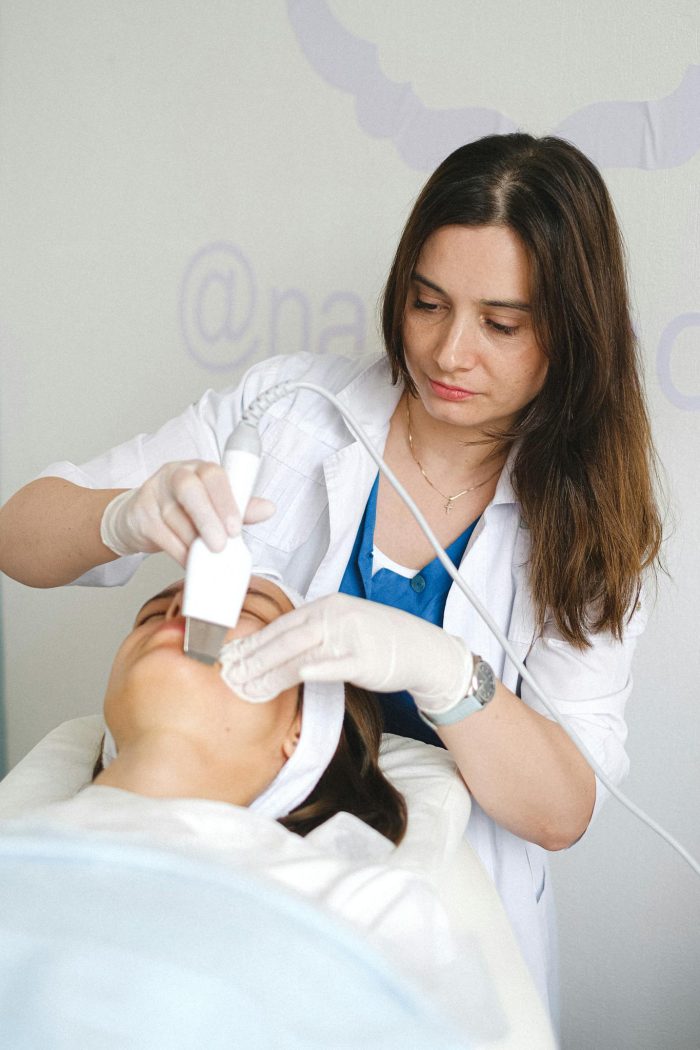 Cosmetologist doing ultrasonic face cleaning to client