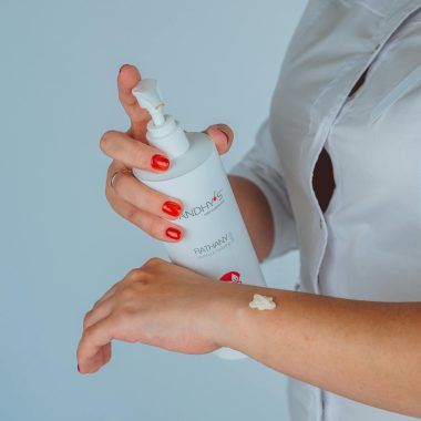 Faceless female cosmetologist applying lotion on hand