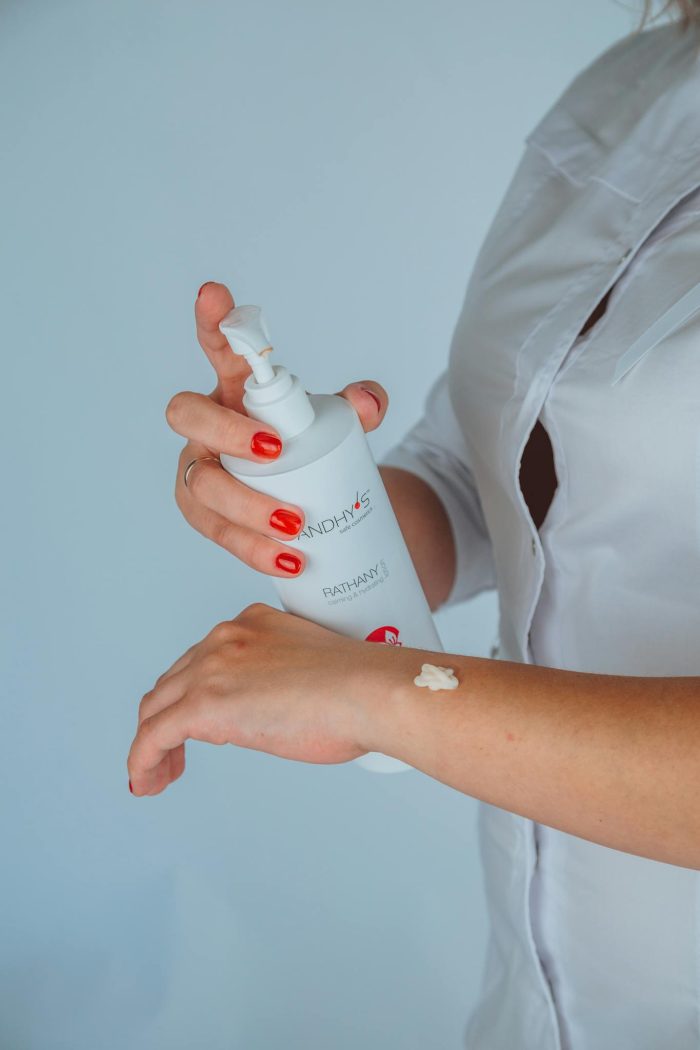 Faceless female cosmetologist applying lotion on hand