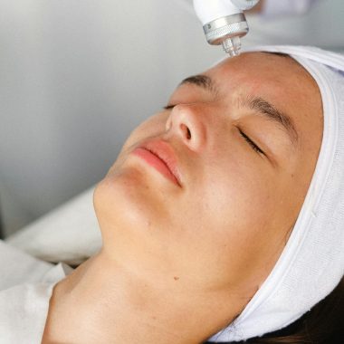 High angle of crop professional cosmetician doing face skin care therapy with laser tool